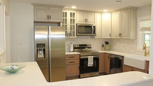 A modern kitchen with stainless steel appliances, white cabinetry, and a marble backsplash. - Time to relax and enjoy (New Bern)