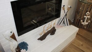 A fireplace with a modern TV above it, surrounded by decorative items. - Time to relax and enjoy (New Bern)