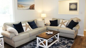 A living room with two beige sofas, starfish pillows, a wooden coffee table, and a patterned rug. - Time to relax and enjoy (New Bern)