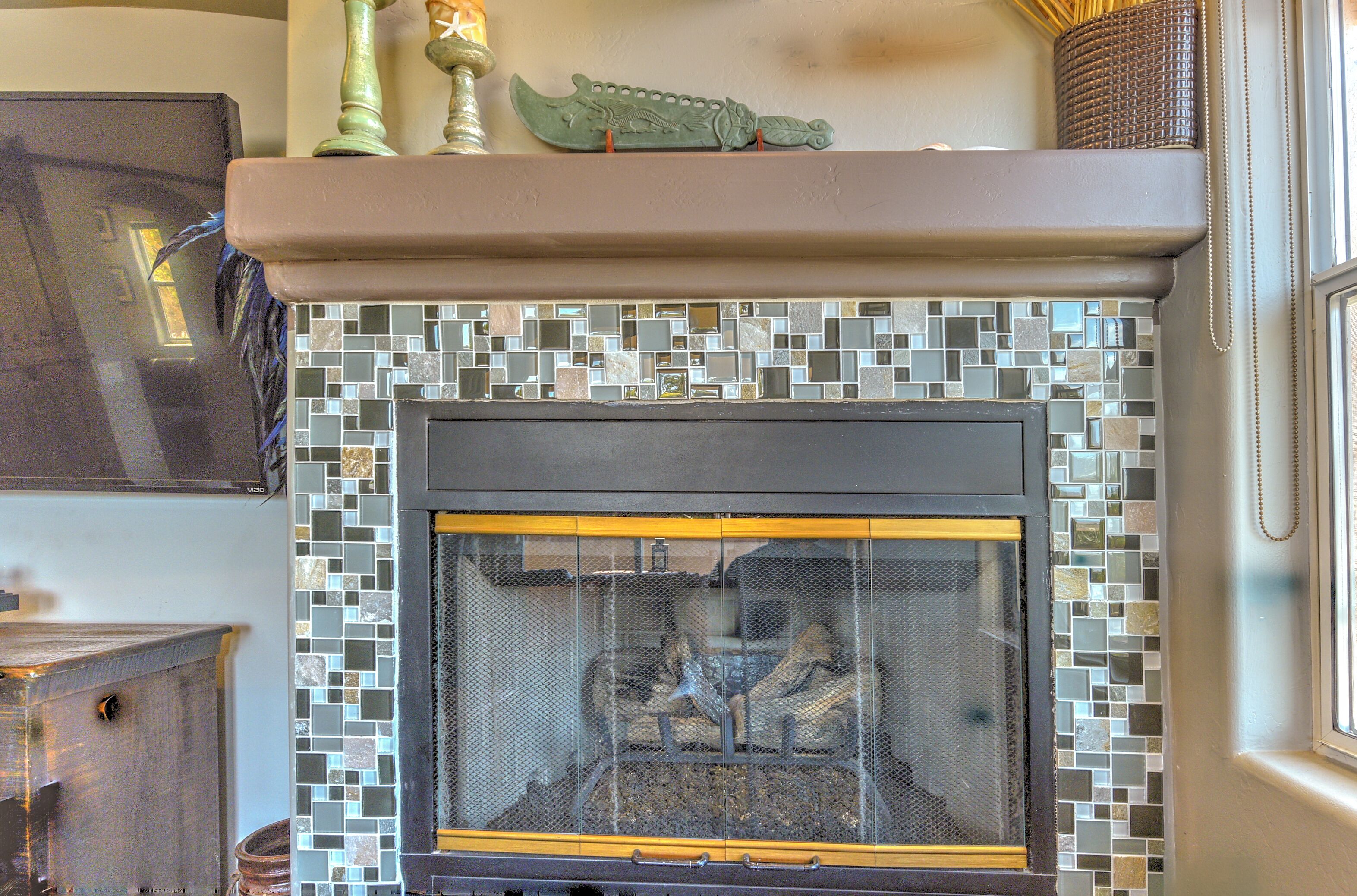 A fireplace with a mosaic tile surround and a decorative crocodile ornament above it.