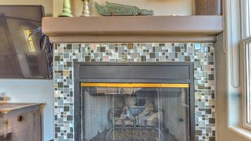 A fireplace with a mosaic tile surround and a decorative crocodile ornament above it.