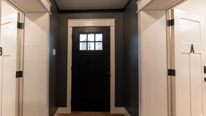 A hallway with a dark door, white walls, and wooden flooring. - Stylish 1BR Downtown • Near Garden of the Gods (Harrisburg)