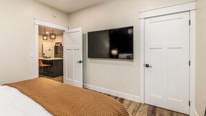 Un dormitorio con una cama, un televisor montado en la pared y un armario.