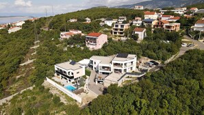 A residential area with modern houses, a swimming pool, and a hilly backdrop.