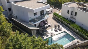A modern two-story building with a rooftop pool, outdoor seating, and a glass balustrade.
