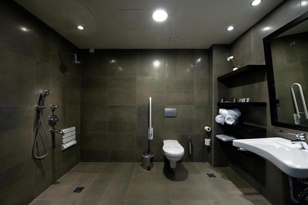 A modern bathroom with a shower, toilet, and sink.
