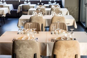 A restaurant with tables set for dining, each with a wine glass, cutlery, and plates. - Ananti Resort & Spa (Trikala)