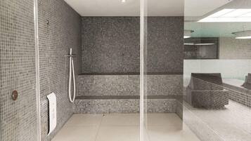 Un baño moderno con cabina de ducha de vidrio, paredes con azulejos y una zona de lavabo a la vista.