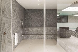 A modern bathroom with a glass shower enclosure, tiled walls, and a visible sink area. - Ananti Resort & Spa (Trikala)