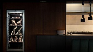 A kitchen with a built-in refrigerator containing meat, a sink, and a stack of plates on the counter. - Ananti Resort & Spa (Trikala)