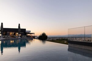 Una piscina infinita moderna con vistas despejadas del paisaje urbano y montañas al fondo.