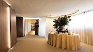 A hotel corridor with a round table set up for a meeting or event, flanked by wooden paneling and a carpeted floor. - Ananti Resort & Spa (Trikala)