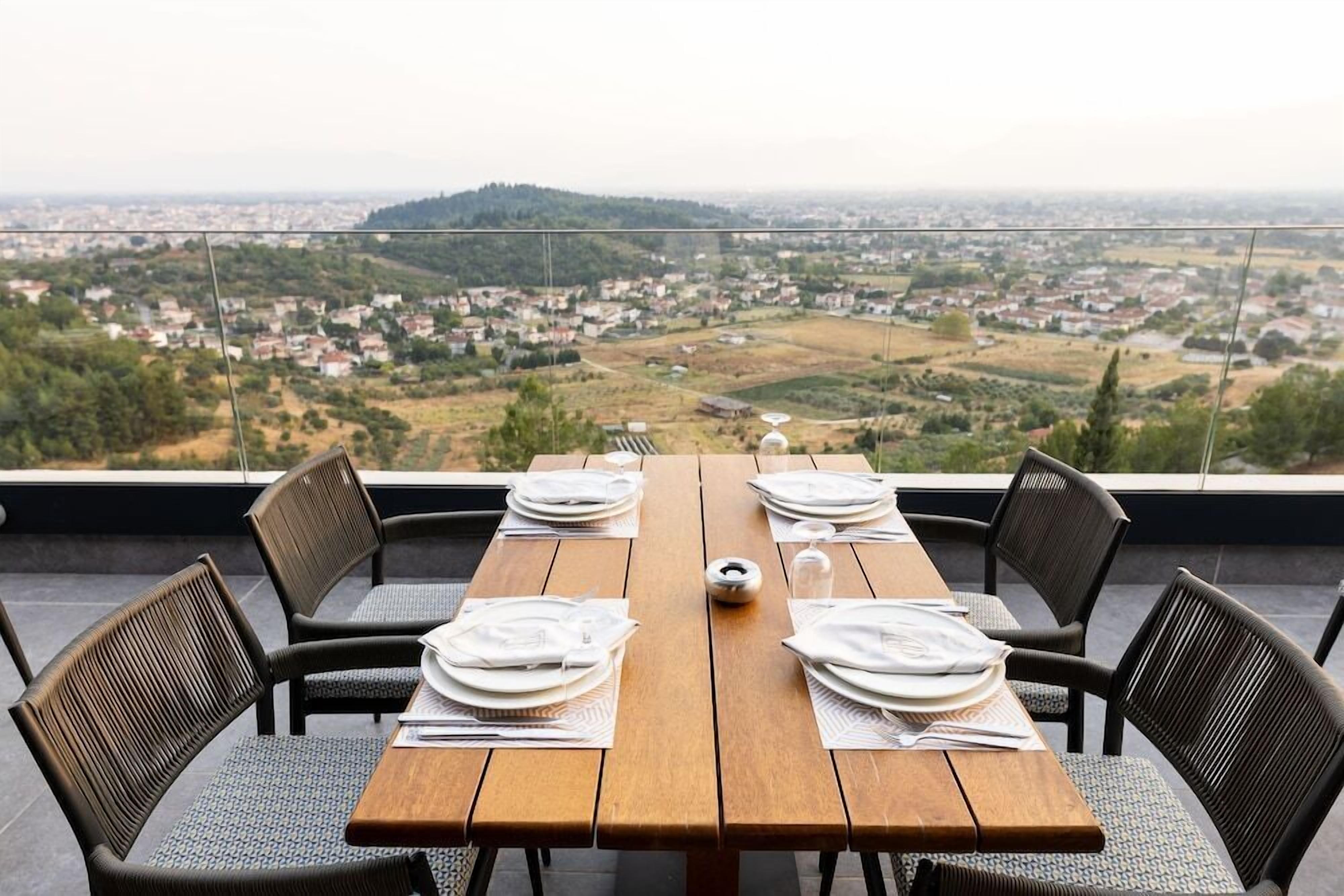 A table set for four with a view of a town and hills in the background.