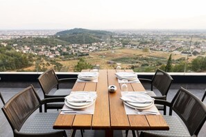 Mesa para cuatro personas con vistas a un pueblo y colinas al fondo.