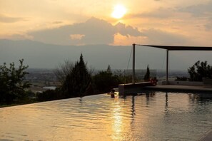 An infinity pool with a view of mountains and a sunset. - Ananti Resort & Spa (Trikala)