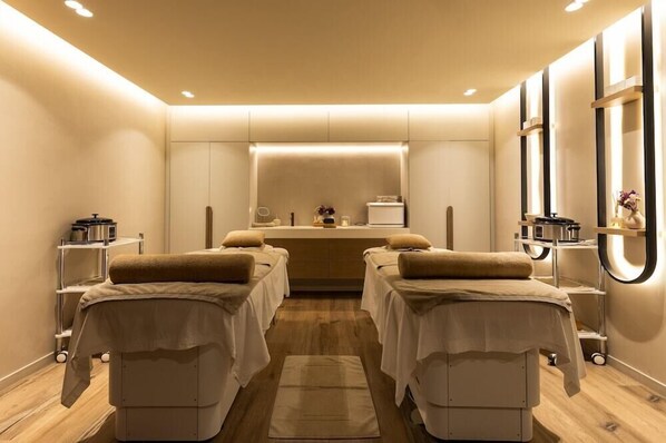 Un cuarto de spa con dos camillas de masaje, un mostrador de recepción y un espejo.