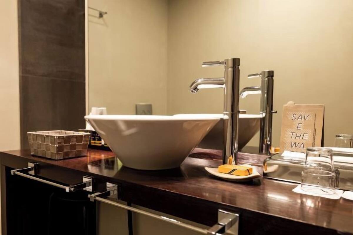 A modern bathroom with a large white vessel sink, a mirror, and a towel rack.