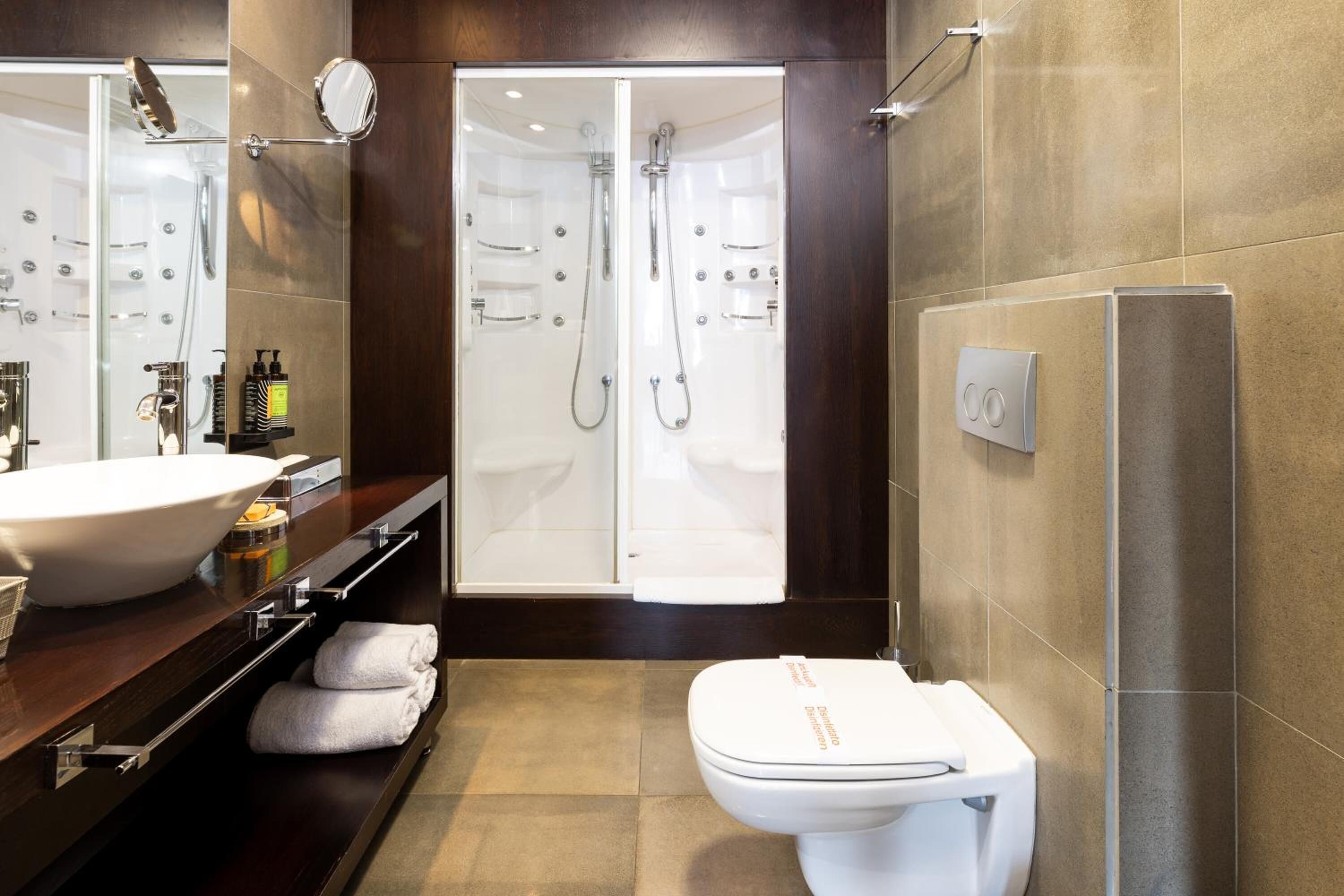 Un baño moderno con un lavamanos grande, un inodoro y una ducha a ras de suelo.