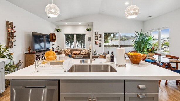 A modern kitchen with a large island, stainless steel appliances, and pendant lighting.