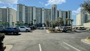 A parking lot with multiple cars and a row of high-rise residential buildings in the background. - Phoenix VI 6013 Few Steps to Pool & Beach! (Orange Beach)