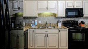 A kitchen with beige cabinets, a granite countertop, a black microwave, and a stove. - Phoenix VI 6013 Few Steps to Pool & Beach! (Orange Beach)