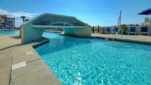 A modern pool area with a unique arched glass bridge, clear blue water, and lounge chairs. - Phoenix VI 6013 Few Steps to Pool & Beach! (Orange Beach)