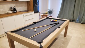 Taula de bitlles en una habitació amb una cuina al fons.