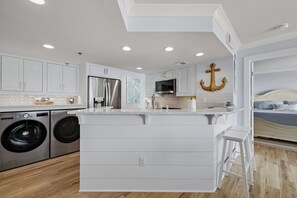 A modern kitchen with built-in appliances, a central island, and a large window.