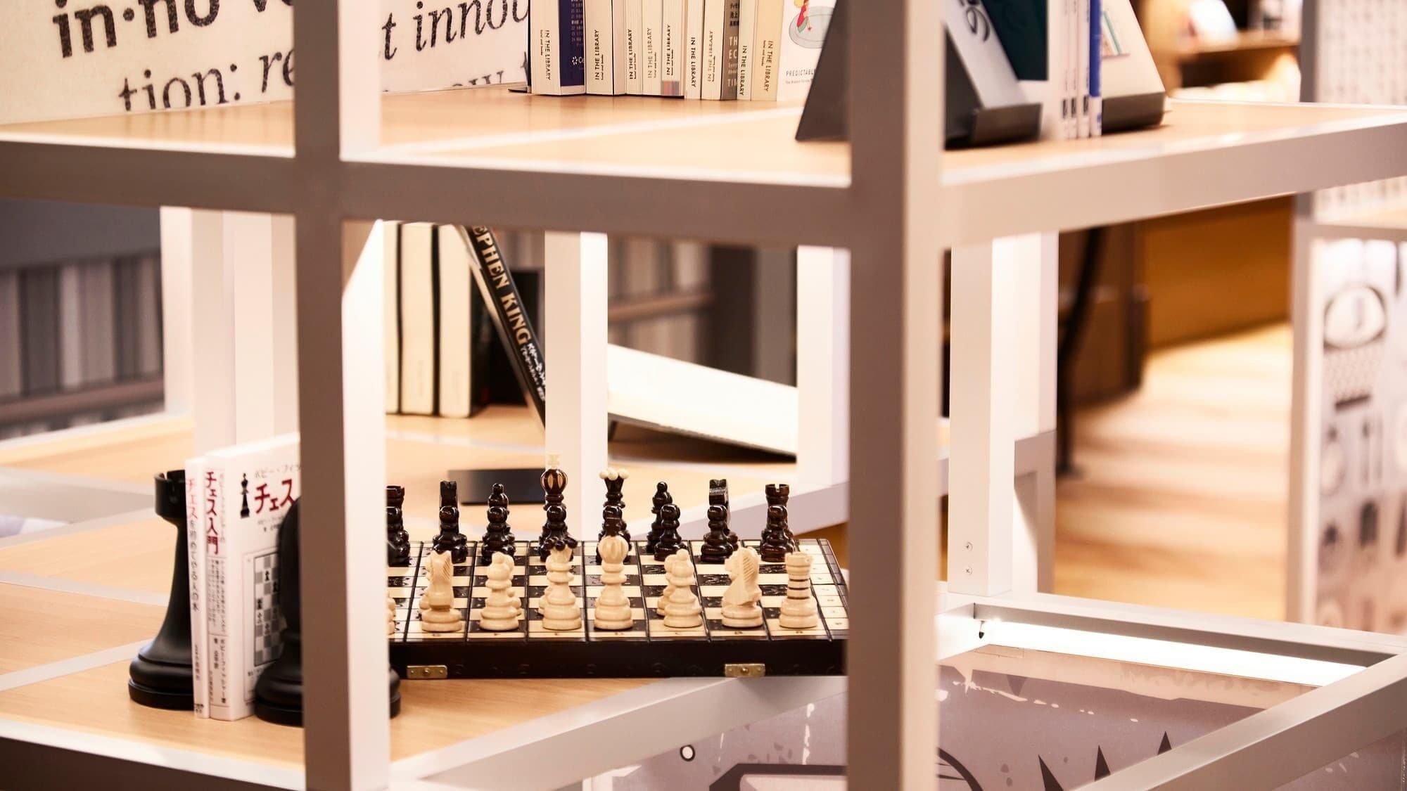 A chessboard on a shelf with books around it.