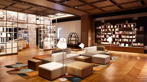 A modern interior with a central seating area, bookshelves, and a unique circular bookshelf. - IN THE LIBRARY hotel and books TOKOROZAWA (Tokorozawa)