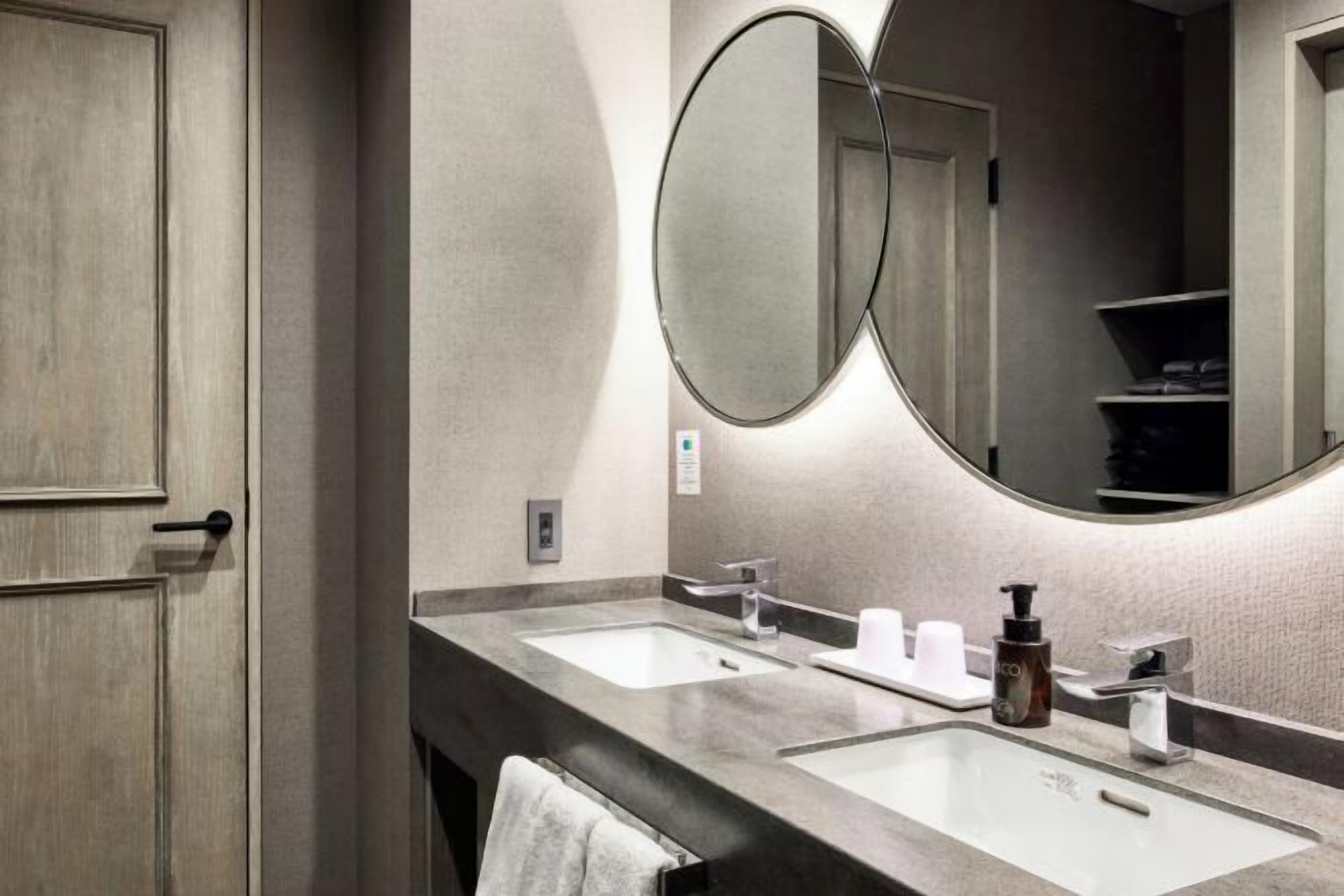 A bathroom with two sinks, a mirror, and a towel rack.