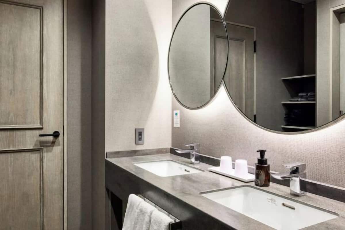 Un bagno con due lavandini, uno specchio e un portascopevoli.
