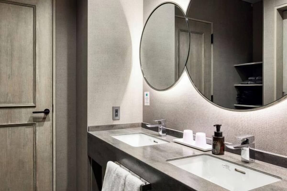 A bathroom with two sinks, a mirror, and a towel rack.