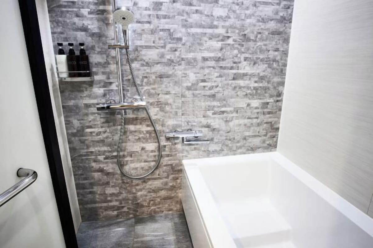 A modern bathroom with a shower, a bathtub, and a shelf with toiletries.