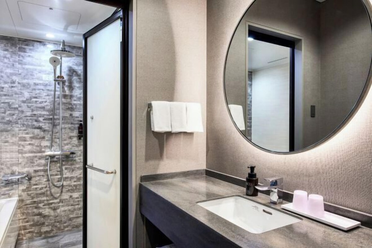 A modern bathroom with a shower, a sink with a mirror, and toiletries.