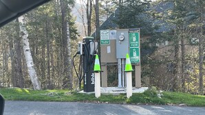 Una estación de carga con un letrero que indica que es solo para vehículos eléctricos durante la carga.