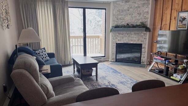 Una sala de estar con sofá, mesa de centro, chimenea y un mueble bajo para la televisión con libros.