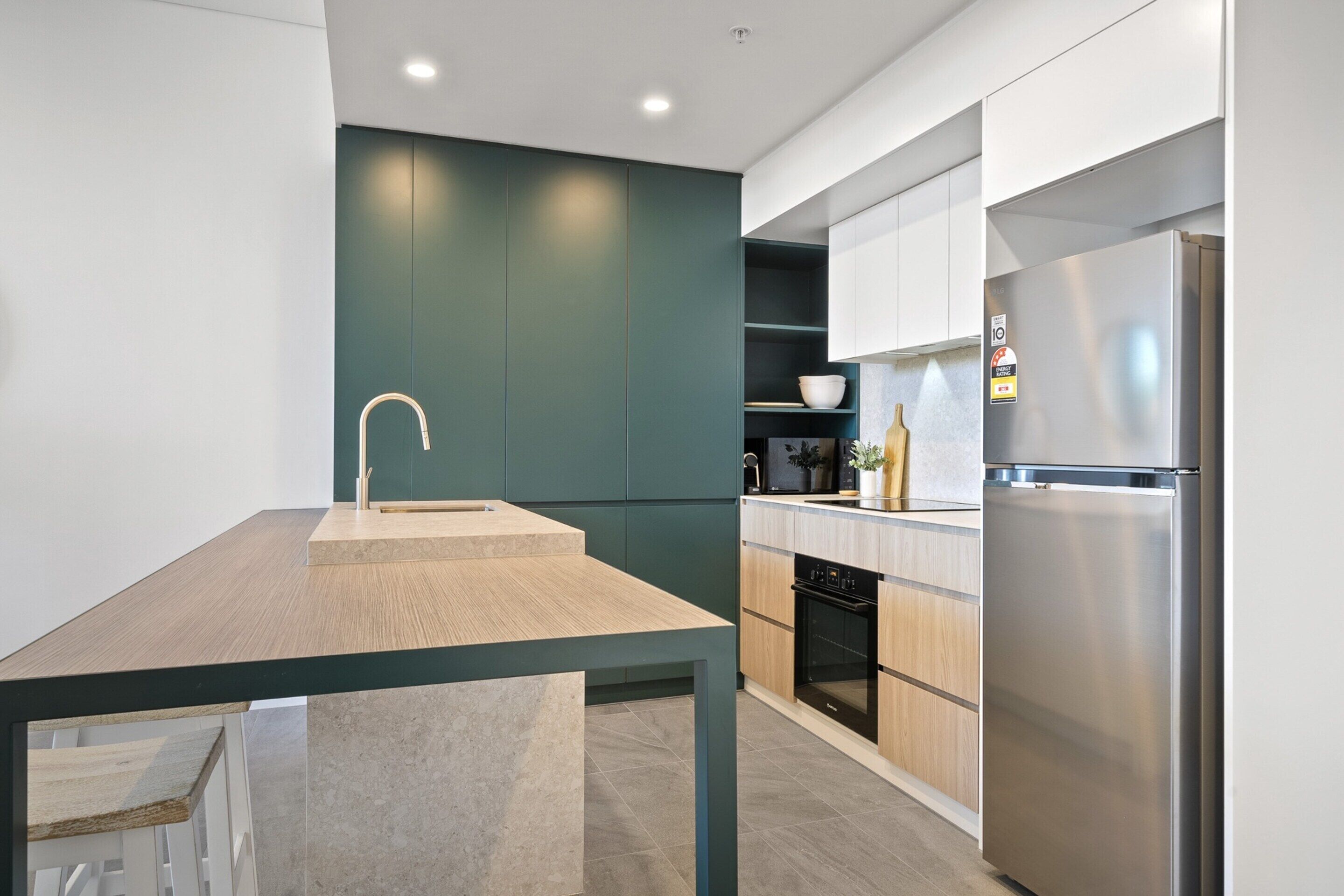 A modern kitchen with a wooden table, a stainless steel refrigerator, and built-in cabinetry.