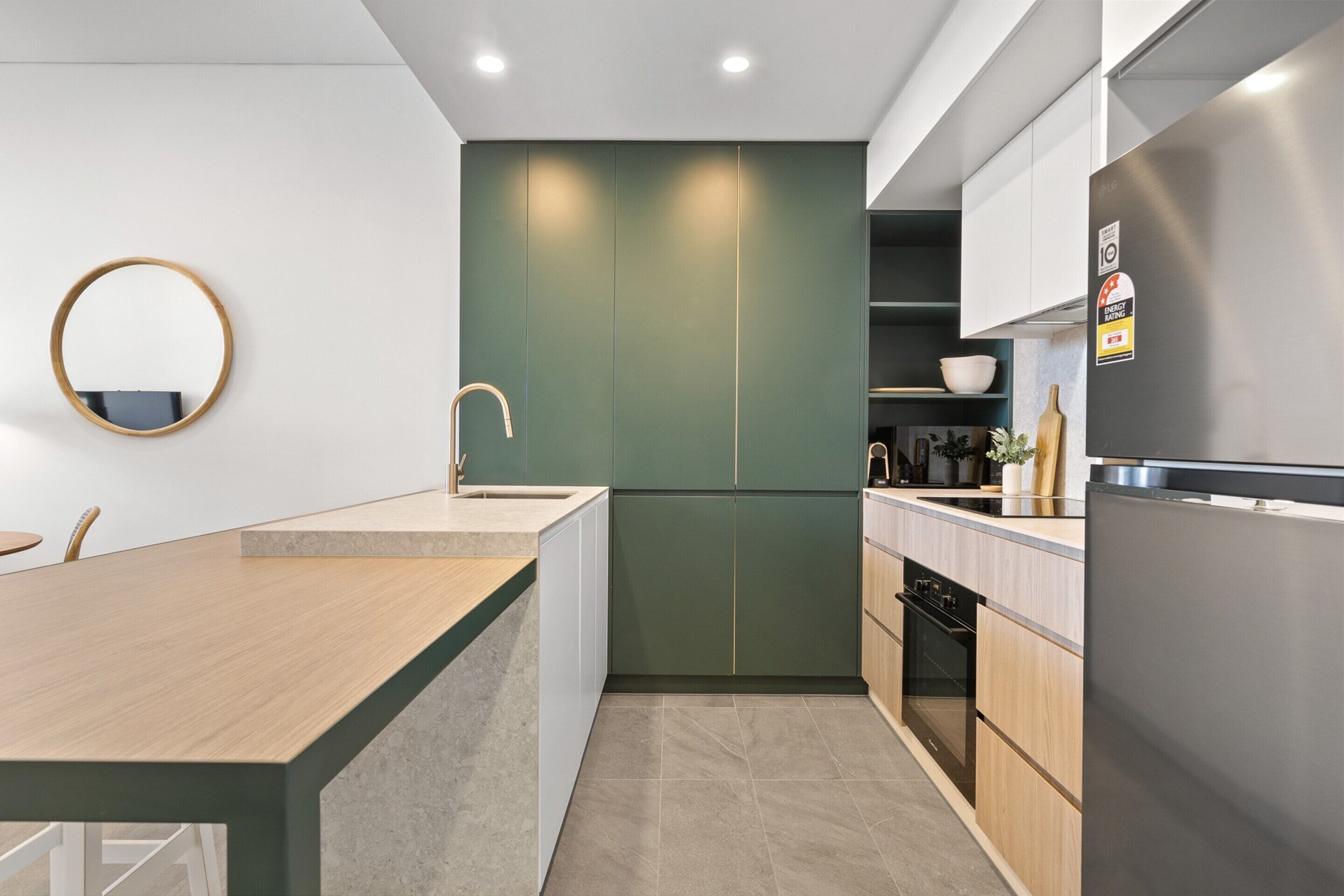 A modern kitchen with a central island, built-in oven, and a stainless steel refrigerator.