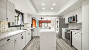 Una cocina moderna con armarios blancos, una isla central y un horno empotrado.
