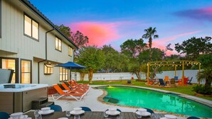 Un patio trasero con piscina, zona de comedor al aire libre y espacio de estar cubierto.