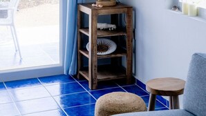 A room with a wooden shelf holding a lamp, a chair, and a small stool. - Uncle Bob`s Reef: Oceanfront Paradise – 1 Bedroom, 2 Bath Townhome (Sabana Westpunt)