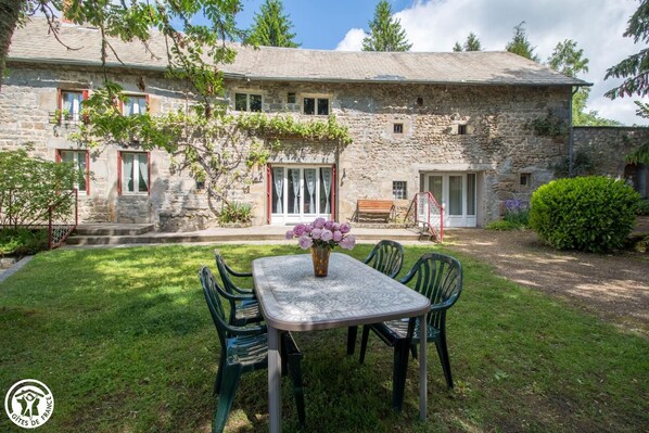 Ein Steinhaus mit Garten, einem Tisch mit Stühlen und einer Bank.