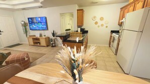 Una cocina moderna con comedor, armarios de madera, televisor y decoración en la pared.