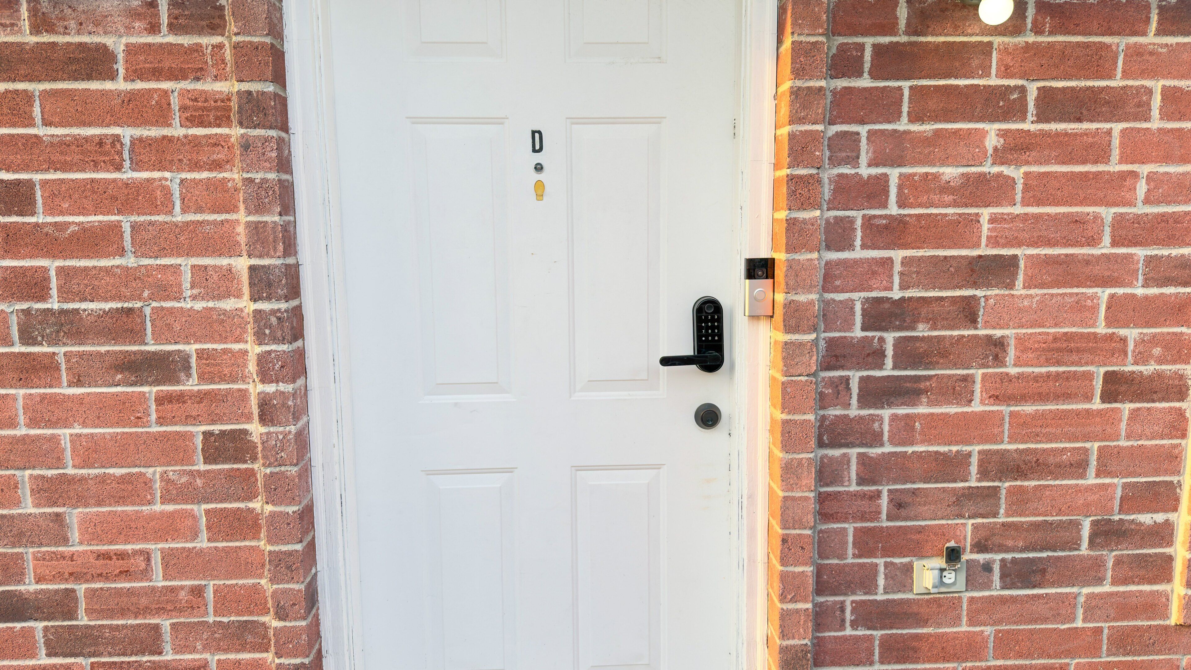A white door with a keypad lock and a doorbell.