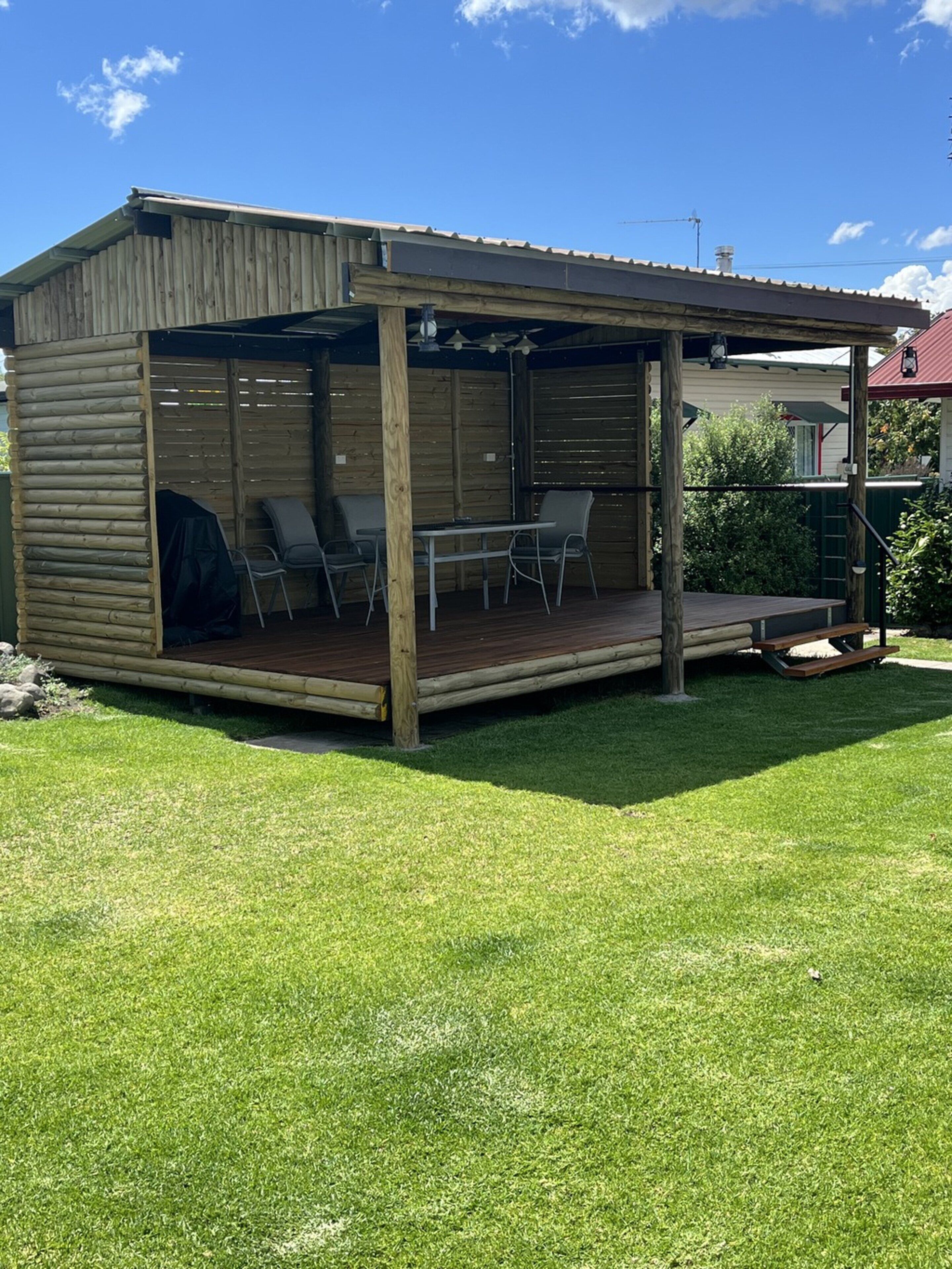 A wooden building with a covered patio, a table, and chairs.