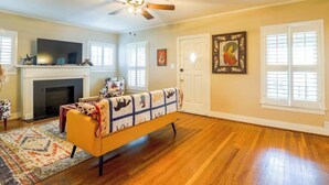 A living room with a fireplace, a sofa, and a ceiling fan. - Vintage Rodeo style home in historic Downtown Weatherford TX. (Weatherford)