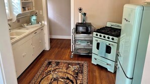 A compact kitchen with a sink, stove, and refrigerator. - Vintage Rodeo style home in historic Downtown Weatherford TX. (Weatherford)