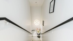 Un escalier au design moderne, agrémenté d’un luminaire et d’une petite table ornée de fleurs.