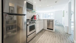 Une cuisine moderne dotée d’appareils électroménagers en acier inoxydable, de meubles blancs et d’un sol à motifs.